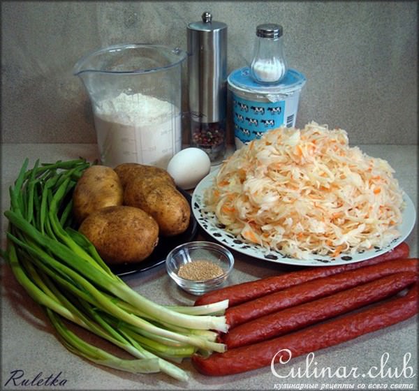 Открытый пирог из картофельного теста с копчёными колбасками и квашеной капустой.
